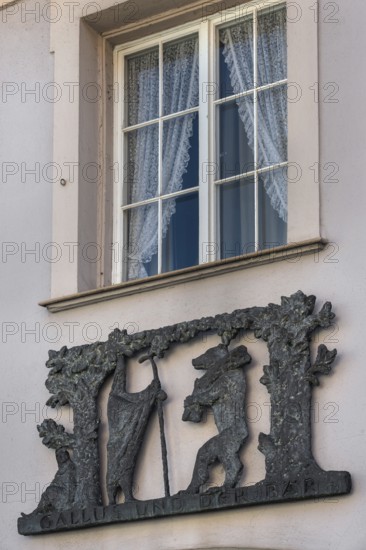Window with blinds and metal relief, Gallus and the bear on the façade of the pharmacy in Kisslegg, Allgäu, Baden-Württemberg, Germany