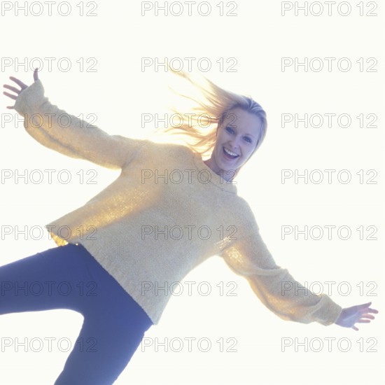 A smiling woman in casual clothes with a bright, light-filled background creating a joyful atmosphere