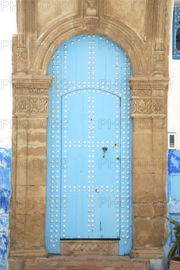 An ancient blue door with an ornate stone archway, featuring a weathered look in a historical structure. Rabat Kasbah des Oudeïas in Marocco