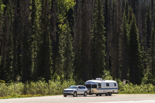 An Airstream travel trailer parked with a car by a dense forest, highlighting travel adventure in side Glacier National Park, near Selkirk, British Columbia, Canada, North America