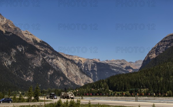 Mountain pass with highway and vehicles, surrounded by forest as viewed from the Trans Canada Highway in British Columbia, Canada, North America