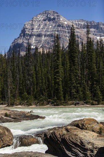 Majestic mountains behind a flowing river with rocky foreground inside Yoho National Park, in British Columbia, Canada, North America