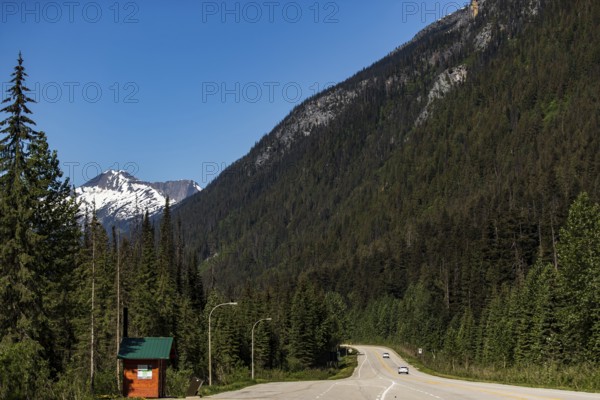Open road curves through mountain pass with snow-capped peaks in the background in Revelstoke, British Columbia, Canada, North America