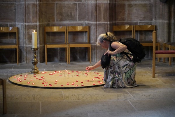 Woman lighting candles in a quiet church room, surrounded by chairs, St Lorenz Church, Nuremberg, Middle Franconia, Franconia, Bavaria, Germany