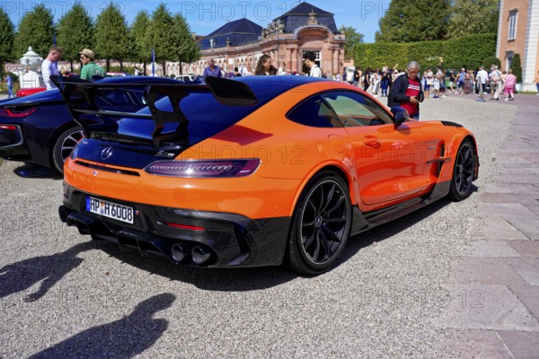 Oldtimer Classic, Gala International Concours d'Elegance Schwetzingen 2025, Germany, Europe, An orange sports car with rear wing in front of a historic building and sky