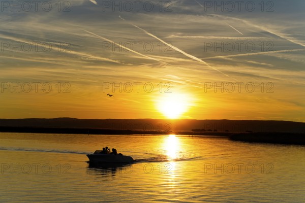 Lake Neusiedl, Burgenland, Austria, Europe, Motorboat leaves gentle waves in the water while sailing into the end of the day, Sailing boats on Lake Neusiedl