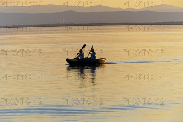 Lake Neusiedl, Burgenland, Austria, Europe, Two people in a canoe, setting in the peaceful dusk, Sailboats on Lake Neusiedl