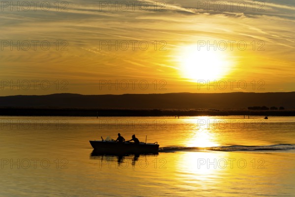 Lake Neusiedl, Burgenland, Austria, Europe, motorboat sailing towards the horizon at an impressive sunset, sailing boats on Lake Neusiedl