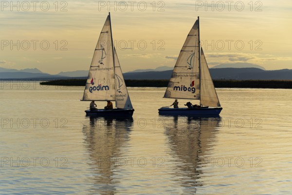 Lake Neusiedl, Burgenland, Austria, Europe, Two sailboats at dusk with mountains on the horizon and calm water, Sailboats on Lake Neusiedl