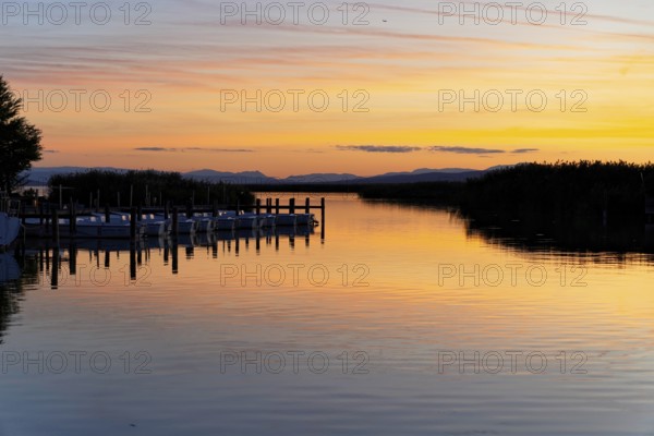 Lake Neusiedl, Burgenland, Austria, Europe, A lake at sunset with quiet boats and a jetty in the warm light, Sailing boats on Lake Neusiedl