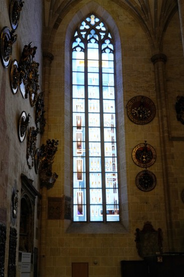 The interior of the largest Protestant church in Germany. It has the world's highest church tower, Ulm Minster, Germany, Europe, High stained glass window in a church, surrounded by decorative coats of arms on the wall, Ulm