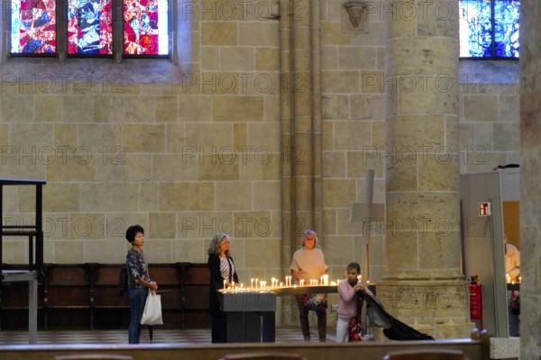 The interior of the largest Protestant church in Germany. It has the world's tallest church tower, Ulm Minster, Germany, Europe, Peaceful scene in the cathedral with people lighting candles in front of a stained glass window, Ulm