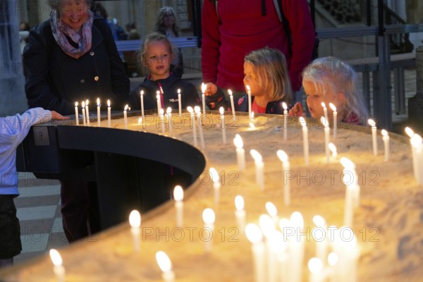 The interior of the largest Protestant church in Germany. It has the world's highest church tower, Ulm Minster, Germany, Europe, Children light candles in a warm, dark atmosphere, Ulm