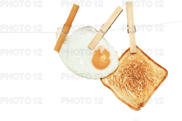 Clothespins holding fried egg and toast on clothesline create unusual breakfast image