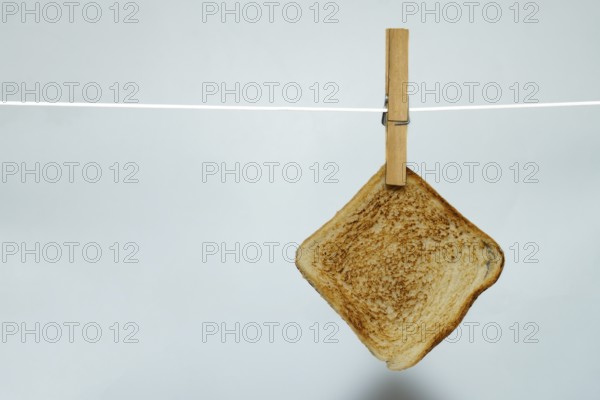 Toasted bread hanging on clothesline with clothespin against white background