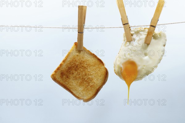 Toast and fried egg hanging from a clothesline with clothespins, representing a simple and unconventional breakfast