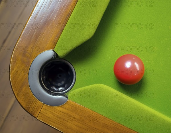 AI generated image showing a billiards table closeup with ball and pocket seen from above