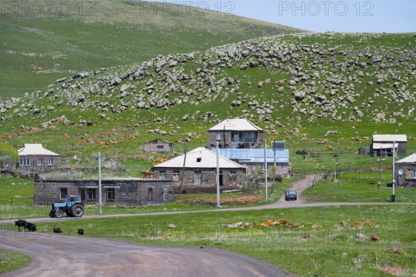 Rural houses on a hillside with a tractor on a road, surrounded by green nature, Zorakert, Lake Arpi, Shirak Province, Armenia