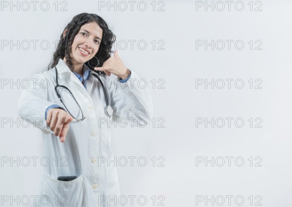 Beautiful female doctor gesturing call isolated. Woman doctor making call gesture and pointing at the camera