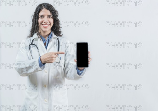 Beautiful woman doctor showing an advertisement on the smartphone screen isolated. Female doctor pointing an app on the phone screen