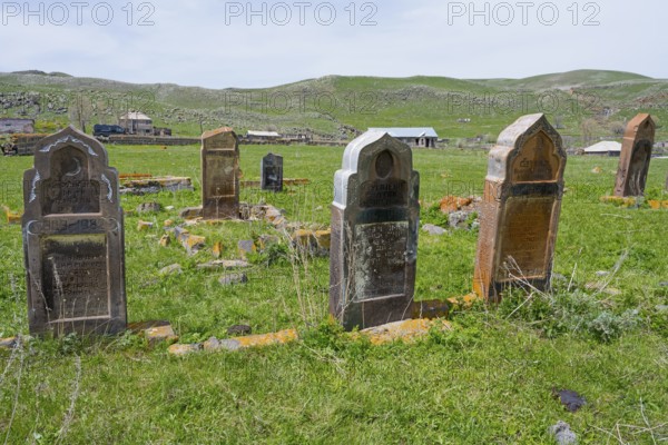 Cemetery with old weathered gravestones on green grassland with rolling hills in the background, old cemetery, Aghvorik, Shirak province, Armenia