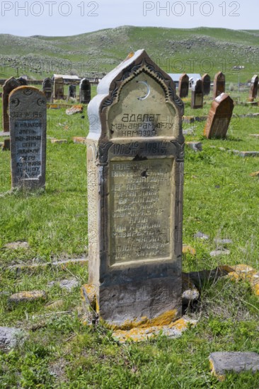 Historic gravestones on a grassy cemetery with hills in the background, old cemetery, Aghvorik, Shirak province, Armenia