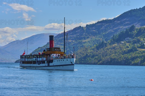 Large ship sailing across a wide lake with picturesque mountain ranges in the background, Queenstown, Queenstown-Lakes District, Otago, South Island, New Zealand