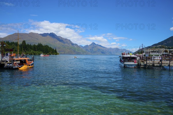 Boats on a jetty with a view of the surrounding mountains and blue water, Queenstown, Queenstown-Lakes District, Otago, South Island, New Zealand