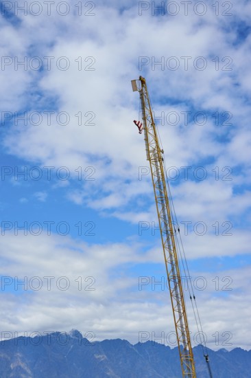 High crane rises into a blue sky with white clouds, mountain landscape in the background, Queenstown, Queenstown-Lakes District, Otago, South Island, New Zealand