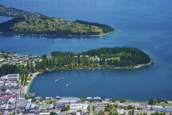 Aerial view of an urban landscape with a blue-green lake and forested peninsulas, Queenstown, Queenstown-Lakes District, Otago, South Island, New Zealand