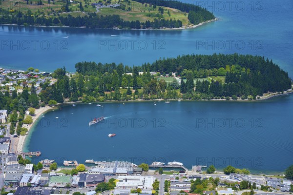 View of a bay with a small island, surrounded by the town and natural surroundings, Queenstown, Queenstown-Lakes District, Otago, South Island, New Zealand