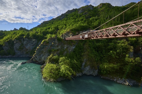 Red suspension bridge with view over the turquoise river and green surroundings, Kawarau Gorge Suspension Bridge, Kawarau River, Queenstown, Otago, South Island, New Zealand