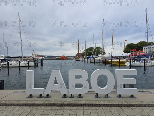 Harbour with large LABOE lettering in the foreground, surrounded by boats and a cloudy sky, Laboe, Kiel Fjord, Schleswig-Holstein, Germany