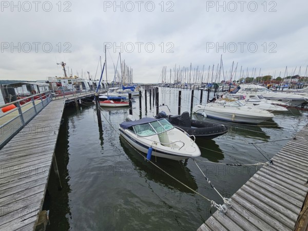 Several motorboats are moored in a harbour, surrounded by jetties and under an overcast sky, Laboe, Kiel Fjord, Schleswig-Holstein, Germany