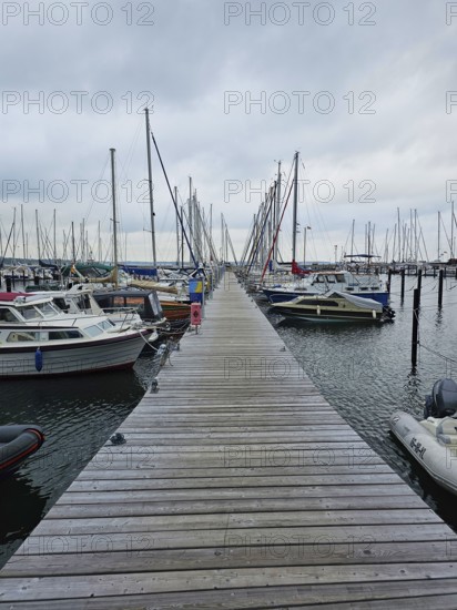 A long jetty runs through a harbour, surrounded by boats and masts on a calm, cloudy day, Laboe, Kiel Fjord, Schleswig-Holstein, Germany