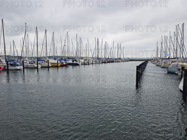 Numerous moored sailing boats in the harbour with cloudy sky, calm sea and parallel jetties, Laboe, Kiel Fjord, Schleswig-Holstein, Germany