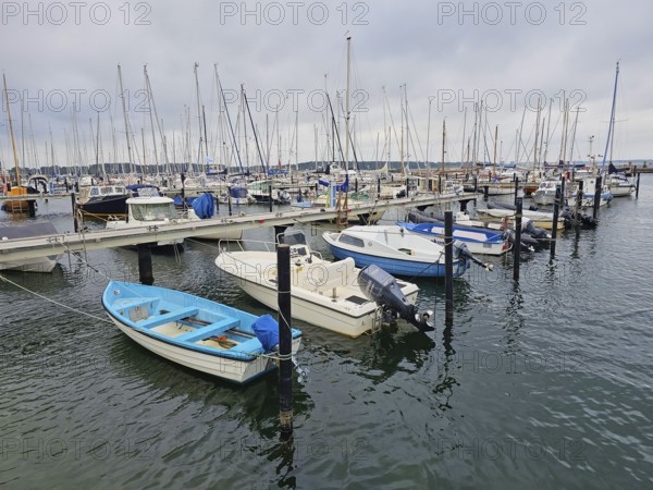 Various boats at a jetty in the harbour with cloudy sky and calm water, Laboe, Kiel Fjord, Schleswig-Holstein, Germany