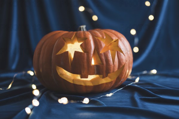 Carved Halloween pumpkin with star eyes glowing on black fabric with festive lights. Generative AI, AI generated