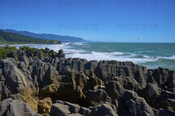 Rough sea meets impressive stacked cliffs under a vast sky, Pancake Rocks, Westport, Greymouth, West Coast, South Island, New Zealand
