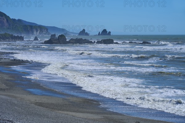 Stormy waves crash against an unspoilt coastline with striking rock formations, West Coast, South Island, New Zealand