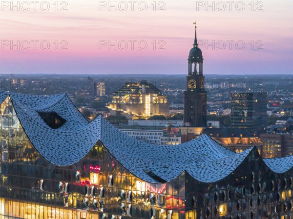 Aerial view of the Elbphilarmonie with St Michael's Church and Hamburg Bunker in the background at blue hour, Hamburg, Germany
