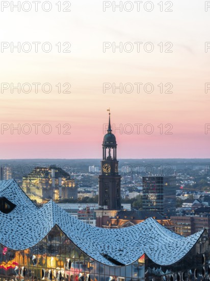 Aerial view of the Elbphilarmonie with St Michael's Church and Hamburg Bunker in the background at blue hour, Hamburg, Germany