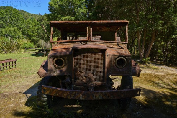 Abandoned, rusty lorry standing in the forest in rustic surroundings, Buller Gorge Swing Bridge, Buller River, Murchison, Tasman, South Island, New Zealand