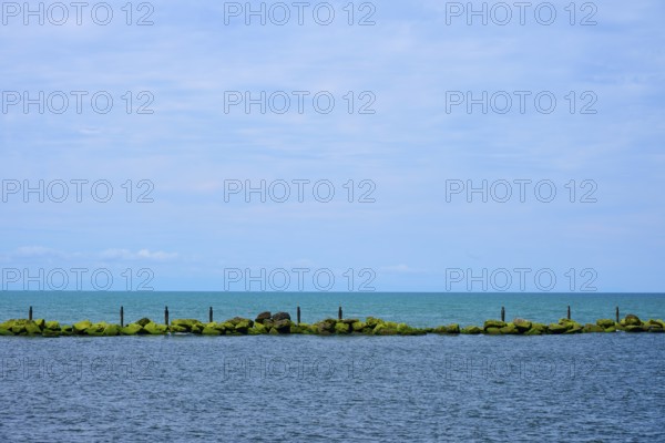 View of the sea with a row of rocks and calm blue sky, Mana Bay, Patea, Taranaki, North Island, New Zealand