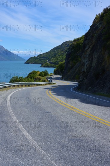 Narrow, winding road meanders along a lake through mountain landscape, Devil's Staircase Lookout Point, Kingston, Lake Wakatipu, Queenstown-Lakes District, Otago, South Island, New Zealand