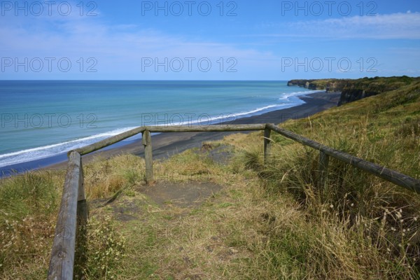 Viewing platform with wooden railing overlooks black sand beach and cliffs on a quiet coast, Mana Bay, Riverview Lookout, Patea, Taranaki, North Island, New Zealand
