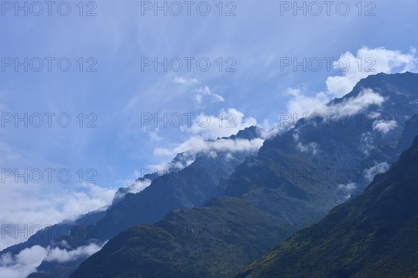 Mountain peak in the foreground with white clouds in the sky, Drift Bay, Lake Wakatipu, Queenstown-Lakes District, Otago, South Island, New Zealand