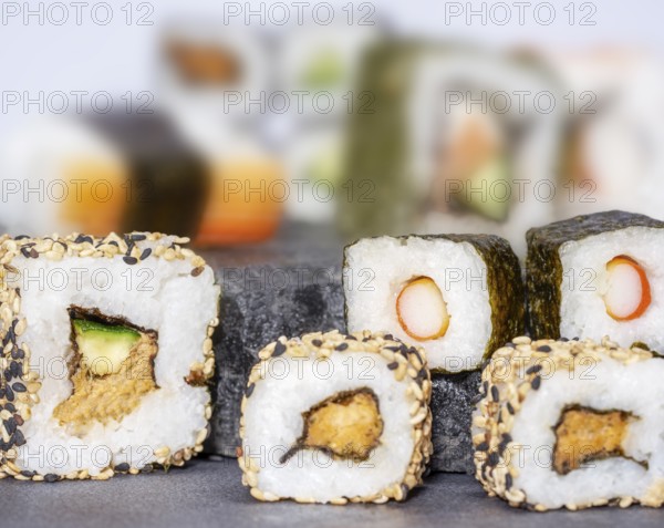 Various sushi dishes on dark grey stone surface