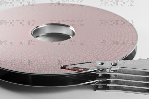 Detail shot of a separated hard disk platter with actuator arm in light grey backAllegory theme regarding operation systems