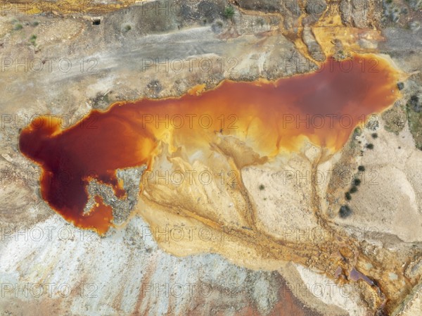 Deep orange-red hues in the water of a pool in the mineral-rich area of the Rio Tinto mines. The colour is caused by oxidised iron minerals. Aerial view. Drone shot. Huelva province, Andalusia, Spain
